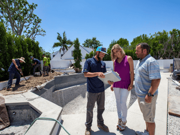 Professional landscape designer and planting crew landscaping backyard near pool